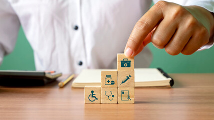 Close-up of human hand stacking wooden blocks overlapping health care icons and medical icons. The concept of choosing health insurance rights when sick