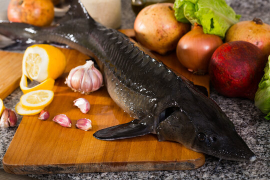 Image of uncooked raw sturgeon at plate near vegetable on table