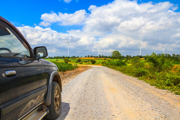 Country road in the cultivated land with turbine in background