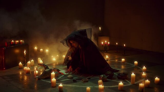 Witch woman sitting in pentagram circle and reading spell. Evil sorceress making rite and sacrifices at night, using black witchcraft, cow skull and candles on floor, full moon. Halloween concept. 