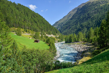 Fototapeta na wymiar River running through green Alps valley landscape