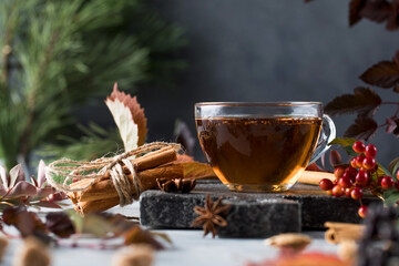 Delicious freshly brewed aromatic tea in a glass cup with a board and various natural ingredients. Tea time