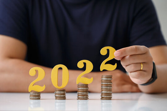  Man Hands Putting Gold Wooden Number 2022 On Stack Of Coins. Tax Payment, Investment And Banking.2022 New Year Saving Money And Financial Planning Concept.