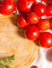 Fragment of a round cutting board with a mountain of tomatoes and a sprig of dill.
