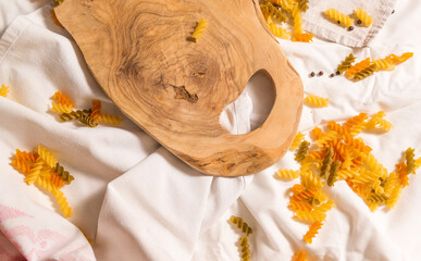The view from above of the cutting board is curved, colored pasta scattered around.