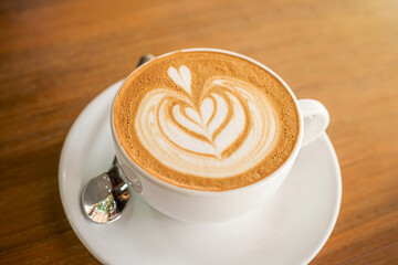 Hot coffee latte with latte art milk foam in cup mug on wood desk on top view. As breakfast In a coffee shop at the cafe,during business work concept