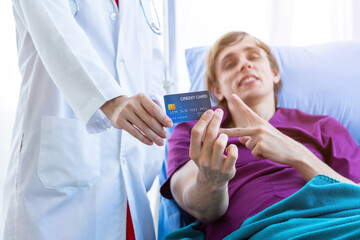 Naklejka premium Female doctor therapeutic advising and a man patient on bed Abstract blur with focus show holding a credit card lying with lifts two fingers up fightingin the room hospital background,payment medical