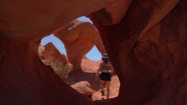 Young Woman Walking Between Strange Natural Arches, Red Sandstone Rock Formation in Valley of Fire State Park, Nevada USA