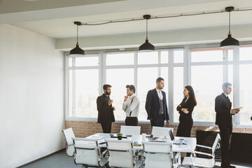 Silhouettes of people against the window. A team of young businessmen working and communicating together in an office. Corporate businessteam and manager in a meeting.