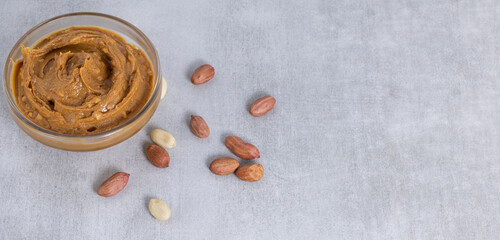 peanut butter and peanuts on gray background with copy space