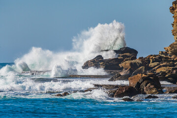 Clear blue skies, splashes on the rocks at the seaside