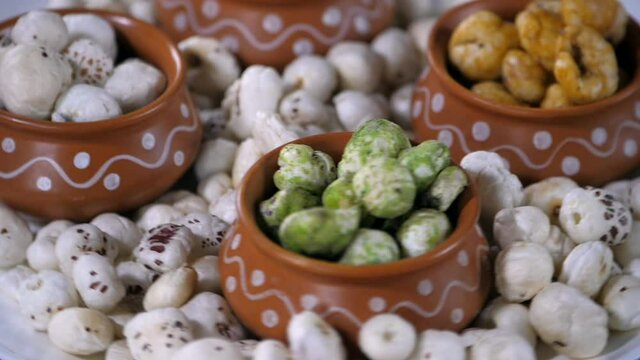 White lotus seeds / Gordon Euryale rotating on a turntable kept on a ceramic plate. Peri-peri  Pudina  and lemon-flavored Makhanas kept nicely in earthen pots - a tasty snack  antioxidant  weight l...