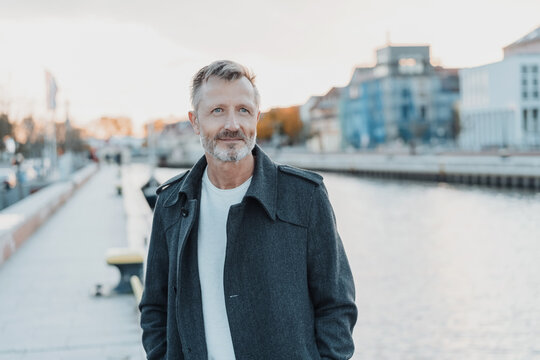 Senior Man Standing Alongside A Canal At Sunset