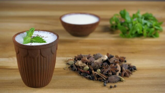 Buttermilk with Jeera is garnished with fresh mint leaves before drinking. Cloves  cardamom  cinnamon  star anise  and a bowl of Dahi in an earthen bowl - cooking ingredients  Indian kitchen  whole...