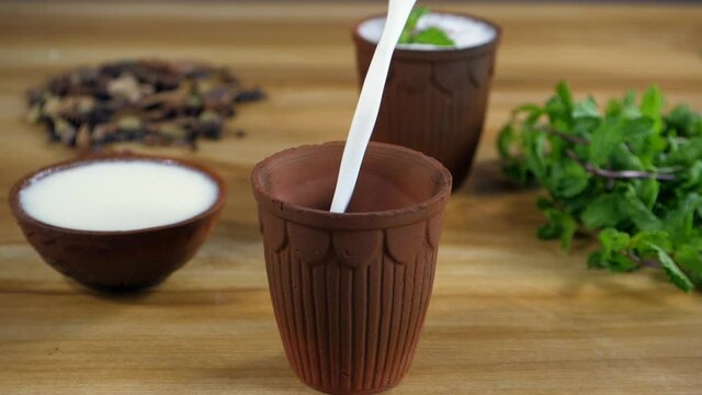 Buttermilk / Chaas pouring in a glass made of clay - a beautiful crockery. Fresh mint leaves  a bowl of curd  and Indian spices kept together - nutritious  cooking ingredients  tasty food  stronger...