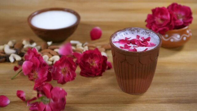 Beautiful red rose and its petals on a wooden table - Rose milk
. A glass of chilled buttermilk  a bowl of yogurt  and some dry fruits kept together - helps in digestion  healthy eating  strong bo...