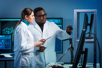 Group of microelectronic engineers discussing in a modern microprocessor manufacture lab. Workplace...