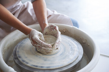 Process of modeling clay dish or pot on potters wheel in studio