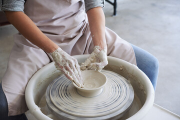 Master class in pottery workshop, woman making dish out of white clay