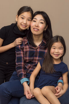 Happy Smiling Asian Family Portrait Of Mom With Braces And Two Daughters On Couch At Home, Moments Together