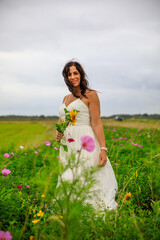 Fototapeta na wymiar Junge hübsche Frau im Brautkleid in einer Blumenwiese