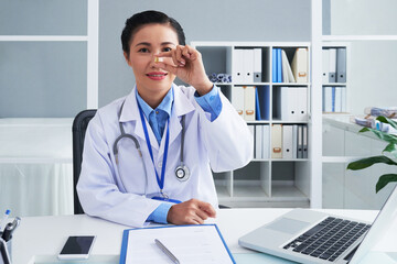 Portrait of positive mature physician showing pill of omega 3 or fish oil she recommends to take...
