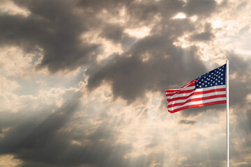Waving flag of United States of America against dramatic sky, copy space. USA symbol in nature environment