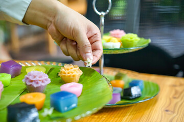 Thai Chef's hand is decorating Varieties traditional colorful Thai desserts set steaming flour, black custard, coconut custard and steaming bean, layer pudding cake