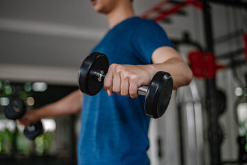 Training gym concept a young adult using his muscular strong arm lifting a dumbbell upward and downward in the gym