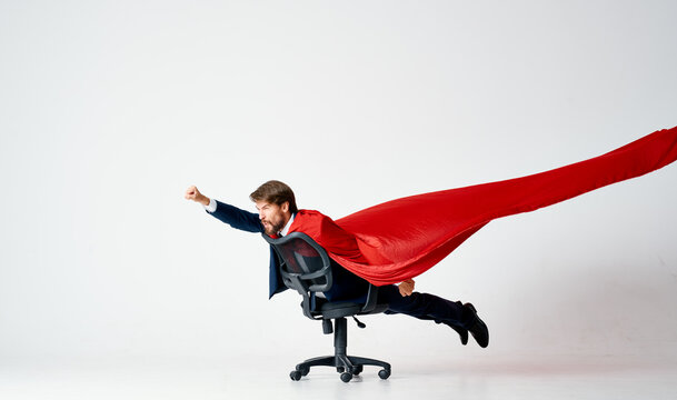 bearded man in a suit rides in a chair red superman cape