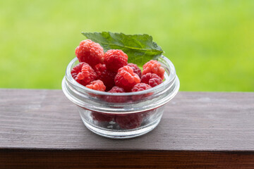raspberries in a glass bowl. wooden brown background