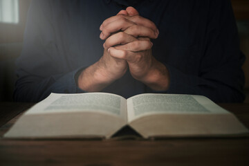 Man is reading and praying the scripture or holy bible on a wooden table with copy space. Religion, believe Concept.
