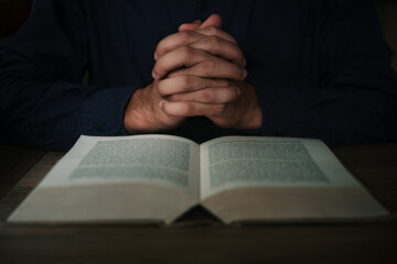 Naklejka premium Man is reading and praying the scripture or holy bible on a wooden table with copy space. Religion, believe Concept.