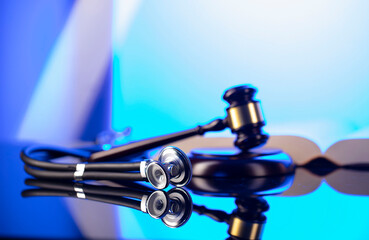 Medical law concept. Gavel, Themis, legal code and stethoscope on the glass table. Blue light.