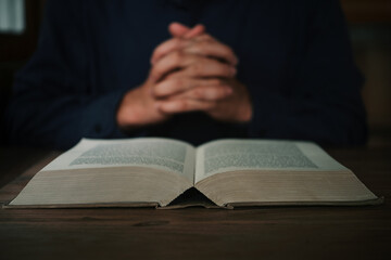 Man is reading and praying the scripture or holy bible on a wooden table with copy space. Religion,...