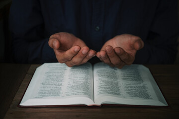 Fototapeta premium Man is reading and praying the scripture or holy bible on a wooden table with copy space. Religion, believe Concept.