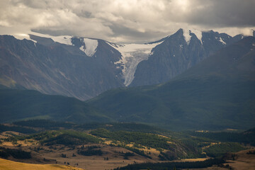 Obraz premium glacier descending from the mountains into the valley with snow, mud and stones on a summer cloudy day russia mountain altai 