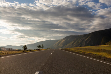 road leading to the mountains and sunset with the sky covered with clouds
