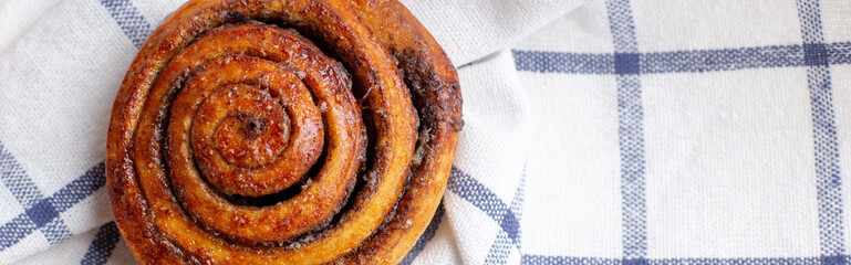 banner of baked cinnamon buns on light background with checkered napkin