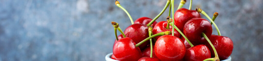 banner of Ripe wet sweet cherries with drops in a blue bowl