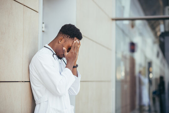 male doctor at the clinic holding his head has health problems and tired after a hard day, depressed did not get the desired result, afro american doctor is sad