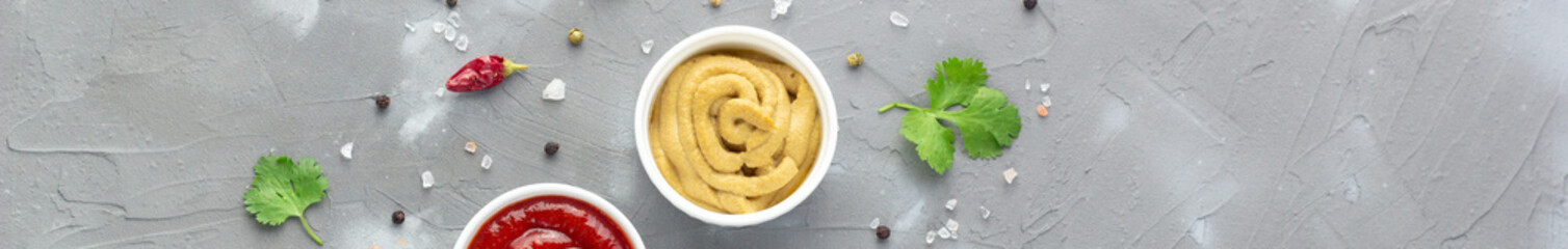 banner of mustard sauce with spices on gray stone background.