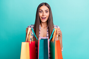 Photo of impressed millennial brunette lady hold bags wear violet shirt isolated on cyan color background