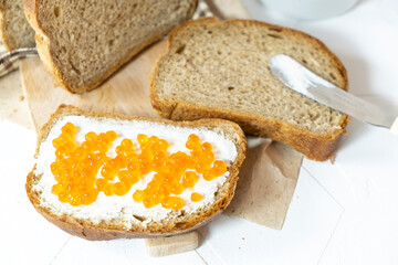 Slices of bread with red caviar on plate on white background. Top view. Copy space.