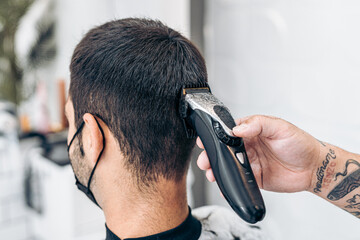 Barber cutting the hair of the nape of a man with a machine in a salon