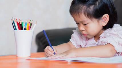 Little kid girl drawing at home creativity development, hands detail of a young children coloring drawing with multicolored pencils.