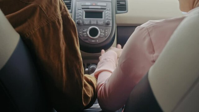 Male and female holding hands, sitting in the car together, romantic gesture