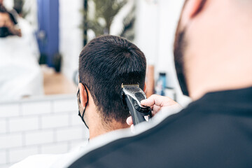 Hair of the nape of a male being cut by a barber with a machine in a salon