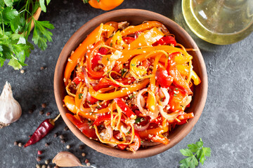 Sweet peppers with carrots, sesame seeds and vegetables in a bowl on a dark background. Top view