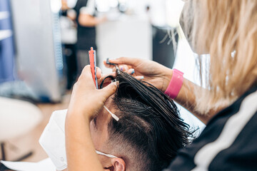 Female hairdresser combing the hair of a man getting a haircut in a salon